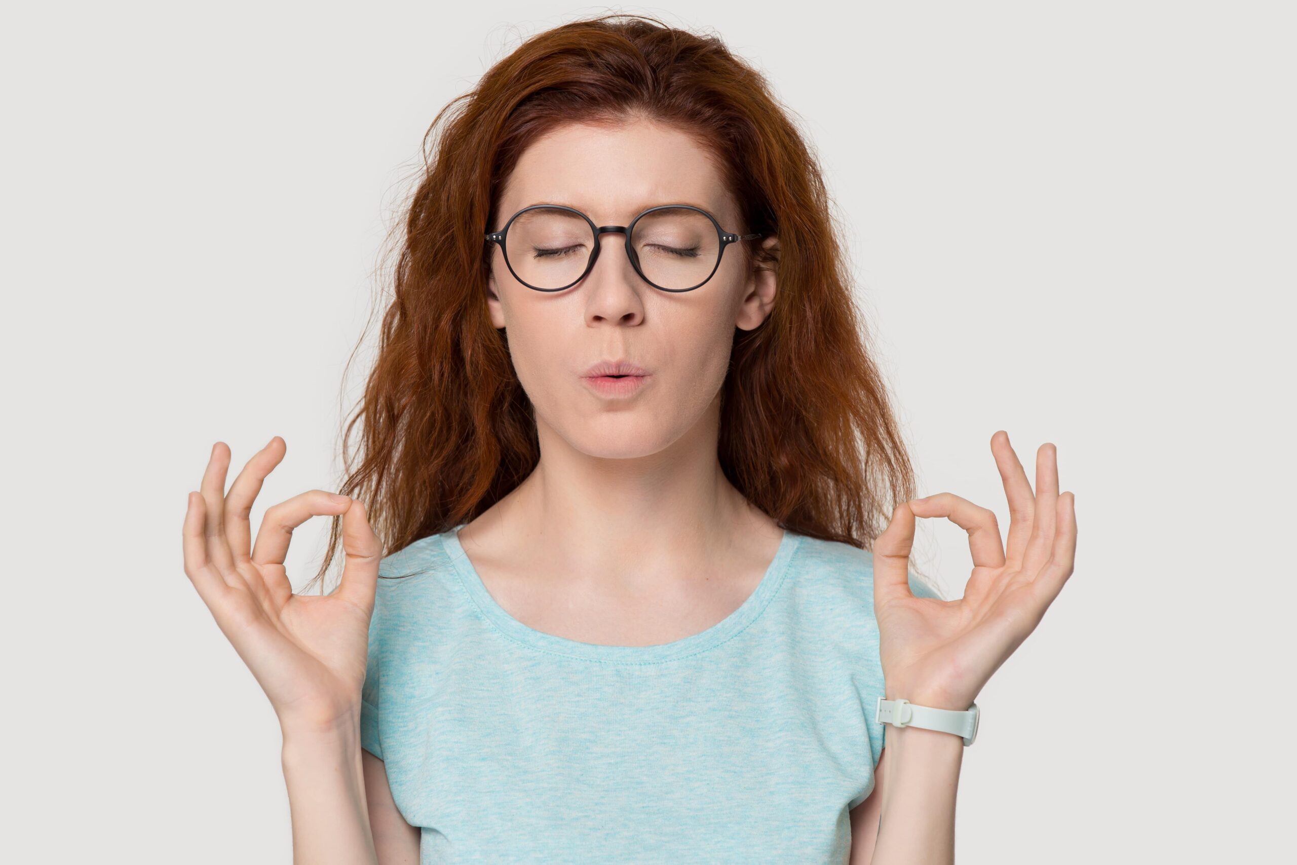 Stressed redhead woman meditating relieving managing stress doing yoga breathing exercises calming down