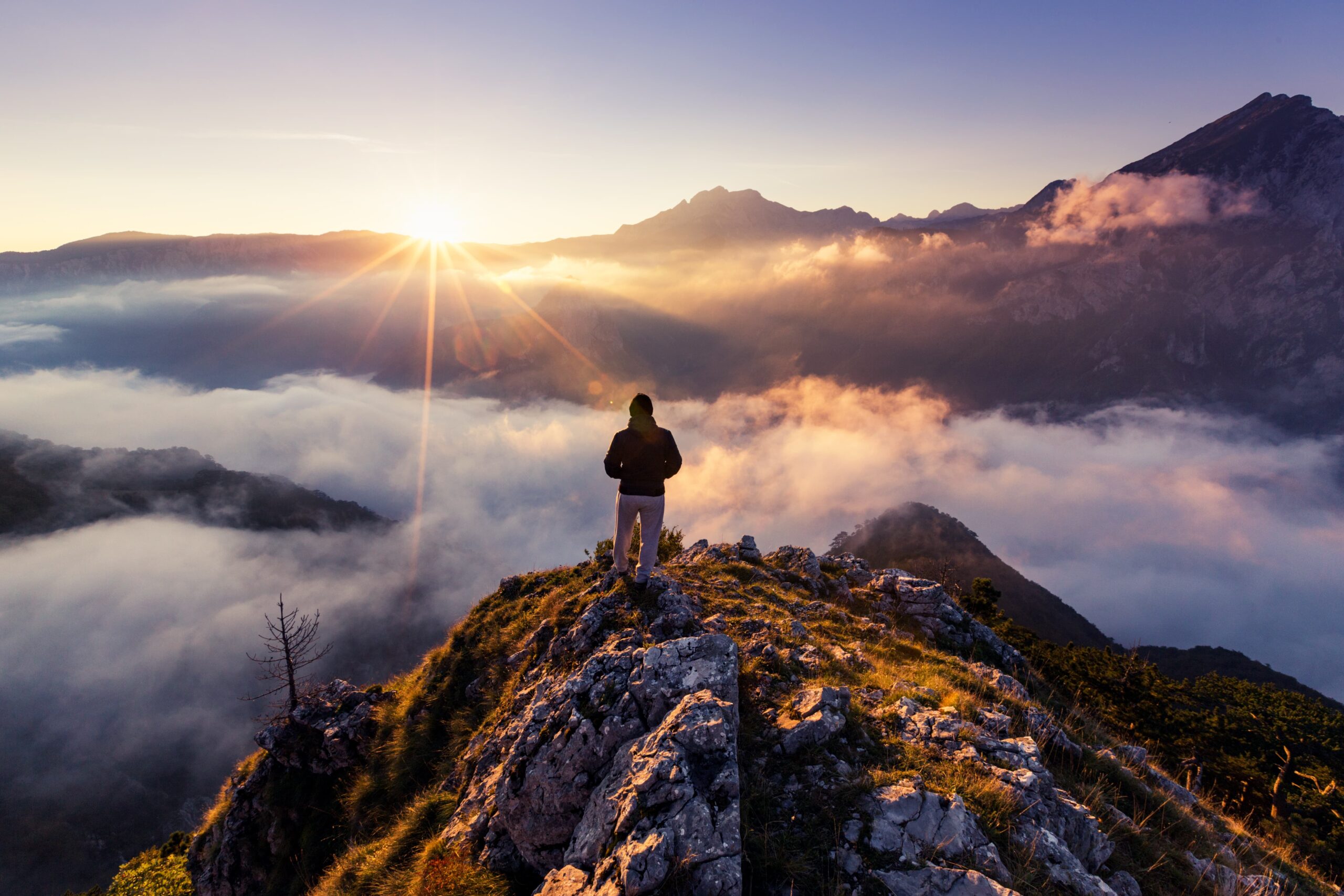 person standing on a mountaintop at sunrise symbolizing recovery success